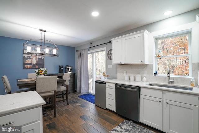 kitchen with hanging light fixtures, sink, stainless steel dishwasher, white cabinets, and dark hardwood / wood-style flooring