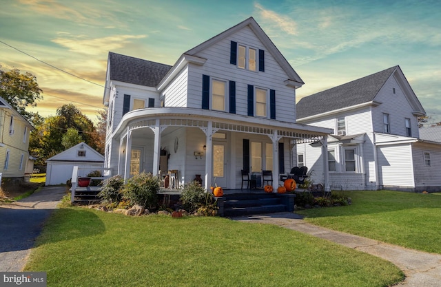 view of front of property with a yard, covered porch, an outdoor structure, and a garage