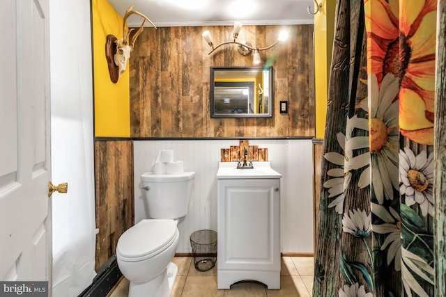 bathroom with vanity, toilet, tile patterned flooring, and wooden walls