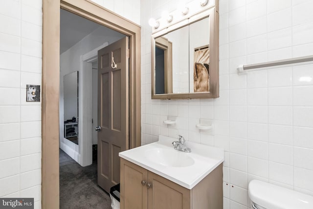 bathroom featuring toilet, vanity, and tile walls