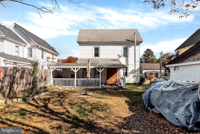 rear view of property featuring a porch and a lawn