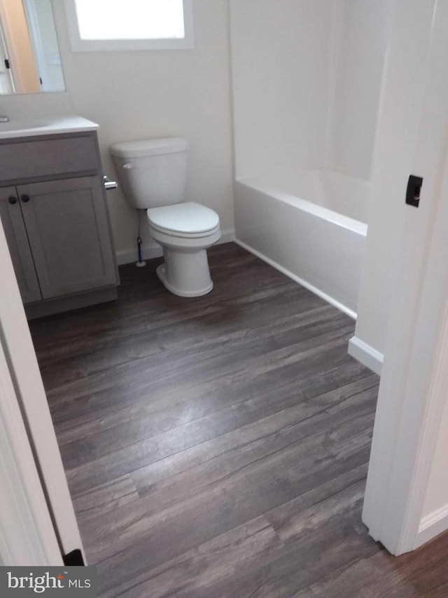 full bathroom featuring hardwood / wood-style floors, vanity, toilet, and bathing tub / shower combination