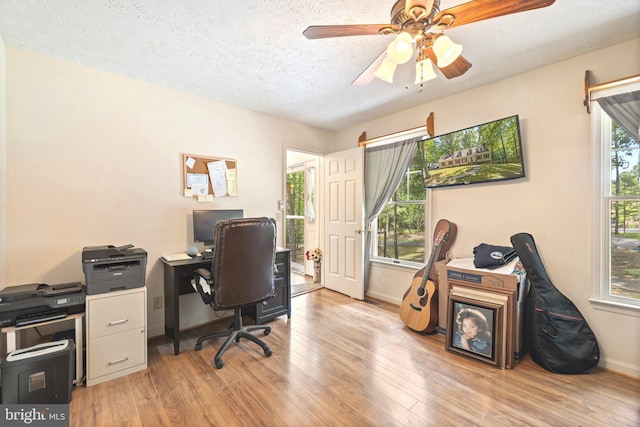 office space with a textured ceiling, light wood-type flooring, and ceiling fan