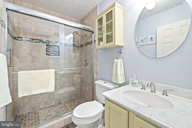 bathroom featuring vanity, a textured ceiling, toilet, and an enclosed shower