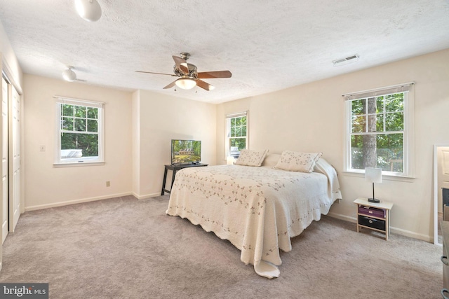 carpeted bedroom with multiple windows, a textured ceiling, and ceiling fan