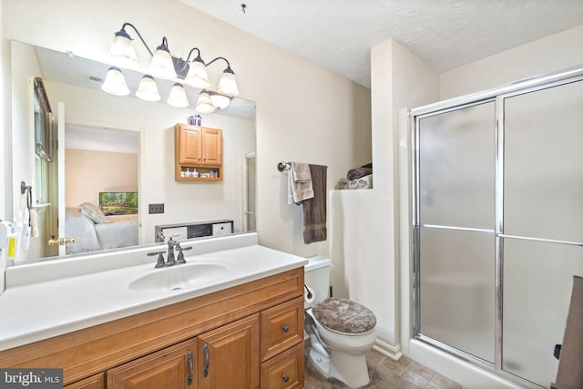 bathroom with vanity, toilet, a textured ceiling, and a shower with shower door