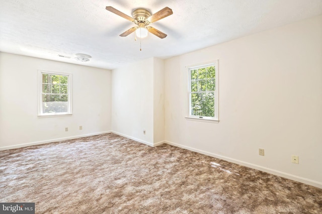 unfurnished room with a textured ceiling, carpet floors, a healthy amount of sunlight, and ceiling fan