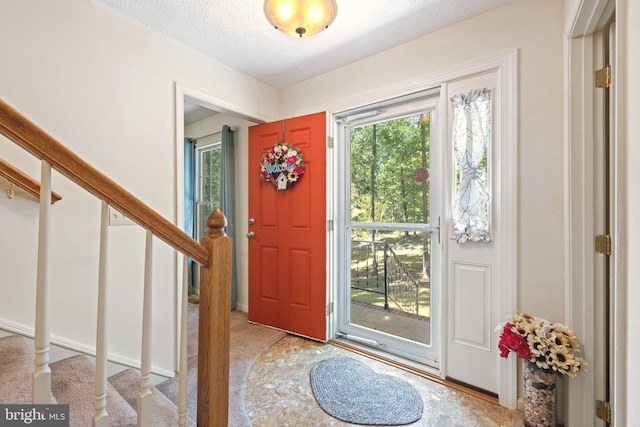 carpeted entrance foyer featuring a textured ceiling