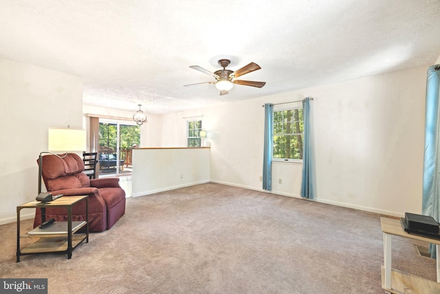 sitting room featuring a textured ceiling, light colored carpet, and ceiling fan with notable chandelier