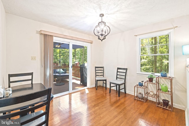 living area with a textured ceiling, hardwood / wood-style flooring, and an inviting chandelier