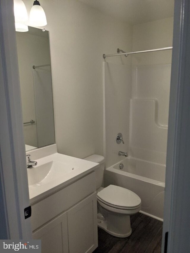 full bathroom with shower / bathing tub combination, wood-type flooring, vanity, and toilet