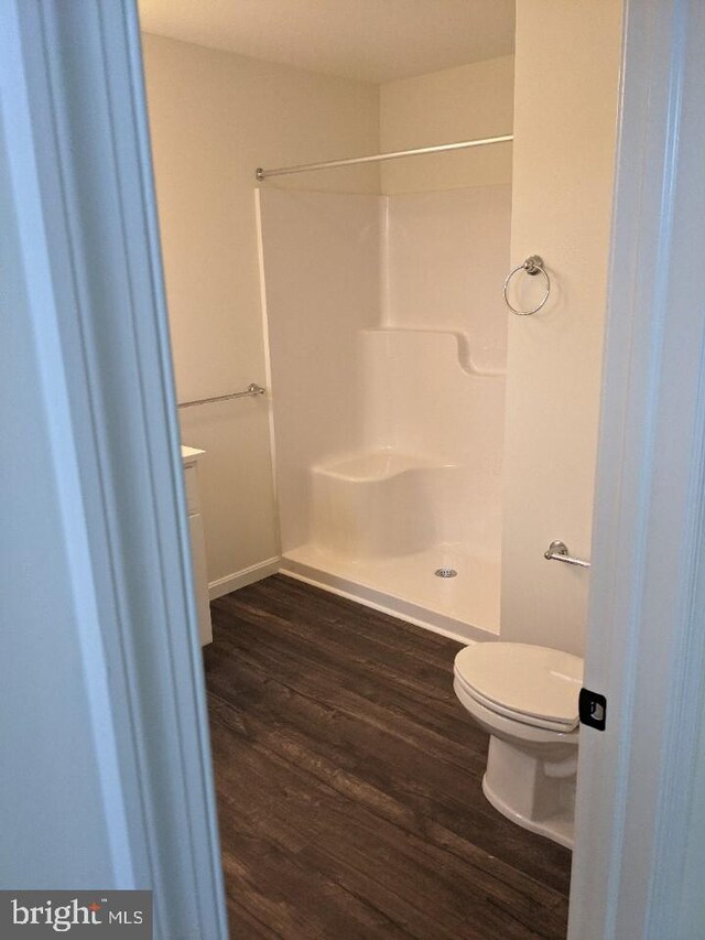 bathroom with a shower, wood-type flooring, and toilet