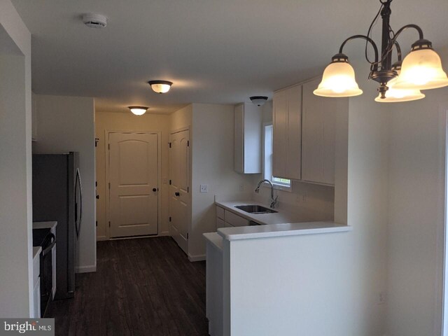 kitchen featuring kitchen peninsula, dark wood-type flooring, sink, white cabinets, and hanging light fixtures