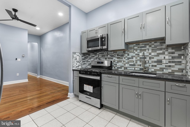 kitchen with gray cabinets, appliances with stainless steel finishes, sink, and light hardwood / wood-style flooring