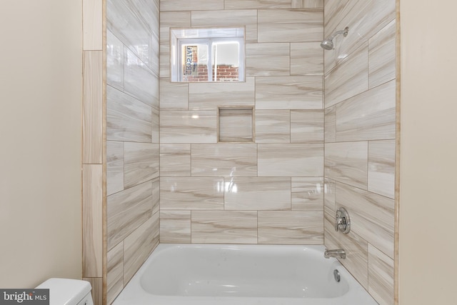 bathroom featuring tiled shower / bath and toilet