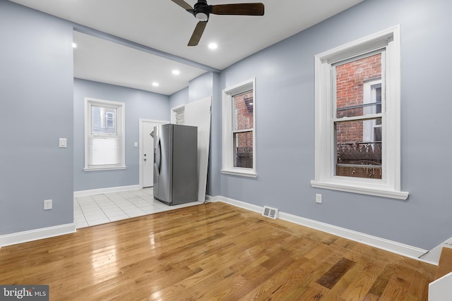 empty room with ceiling fan and light hardwood / wood-style flooring