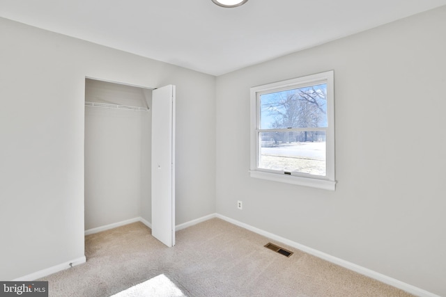 unfurnished bedroom with light colored carpet and a closet