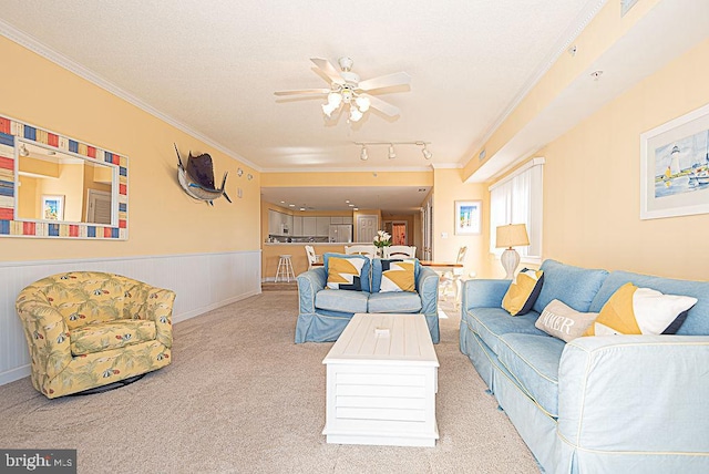 living room with rail lighting, crown molding, light colored carpet, and ceiling fan