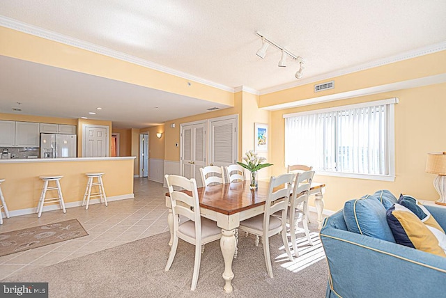 tiled dining room with crown molding and rail lighting