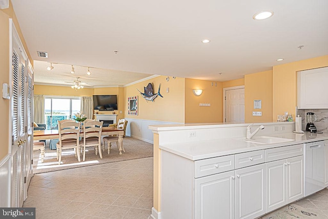 kitchen with tasteful backsplash, sink, kitchen peninsula, white cabinetry, and ceiling fan