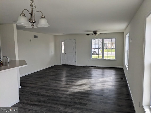 unfurnished living room featuring ceiling fan with notable chandelier, sink, and dark hardwood / wood-style flooring