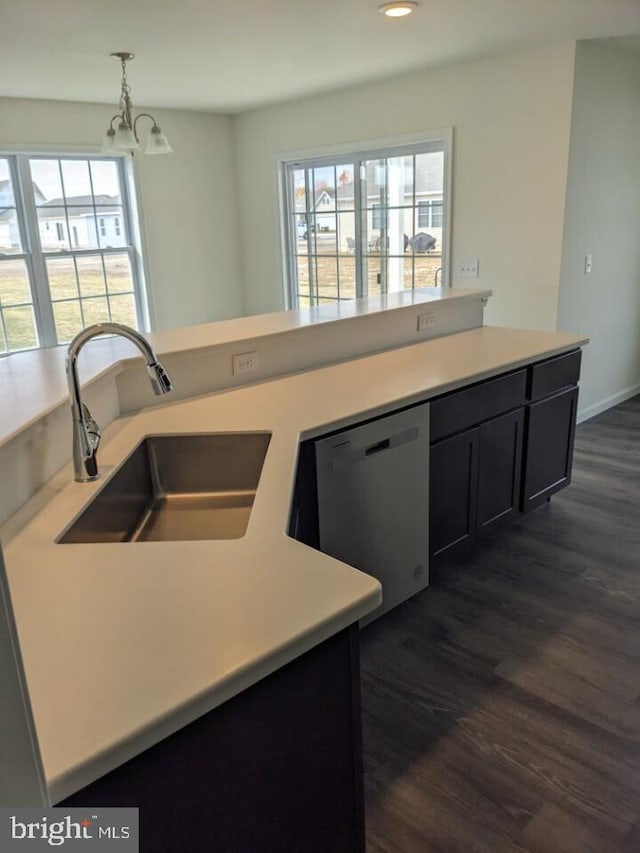 kitchen with dark wood-type flooring, a notable chandelier, sink, stainless steel dishwasher, and pendant lighting