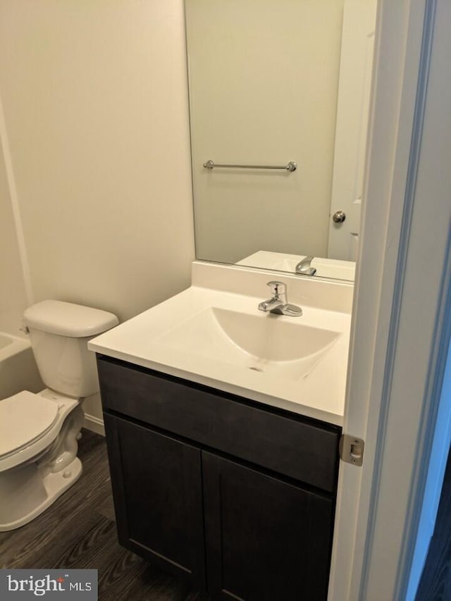 bathroom with hardwood / wood-style flooring, vanity, and toilet