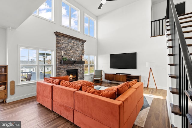 living room with a fireplace, hardwood / wood-style flooring, and a towering ceiling