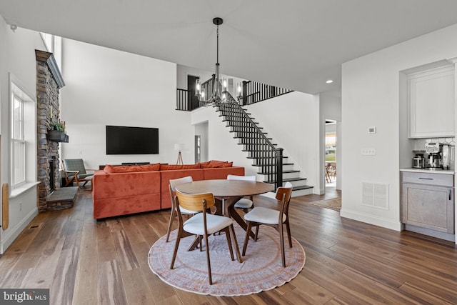 dining area featuring a chandelier, a stone fireplace, and wood-type flooring