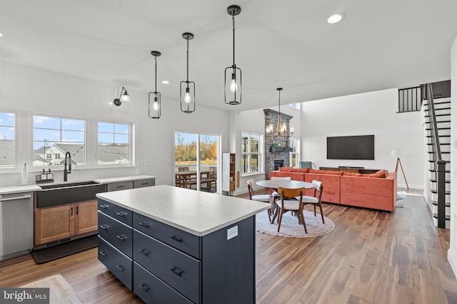 kitchen featuring a kitchen island, light hardwood / wood-style flooring, dishwasher, pendant lighting, and a stone fireplace