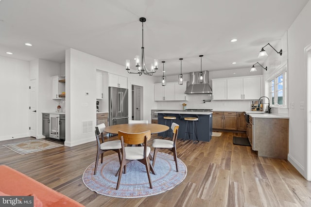 dining room with sink, a notable chandelier, light hardwood / wood-style flooring, and beverage cooler