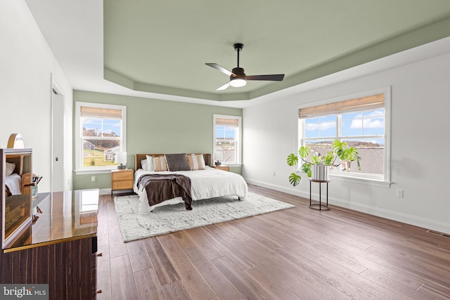 bedroom featuring hardwood / wood-style flooring, a raised ceiling, and ceiling fan