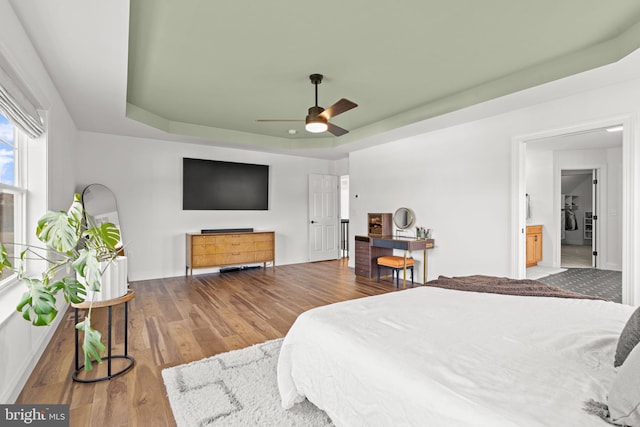 bedroom featuring wood-type flooring, a tray ceiling, and ceiling fan