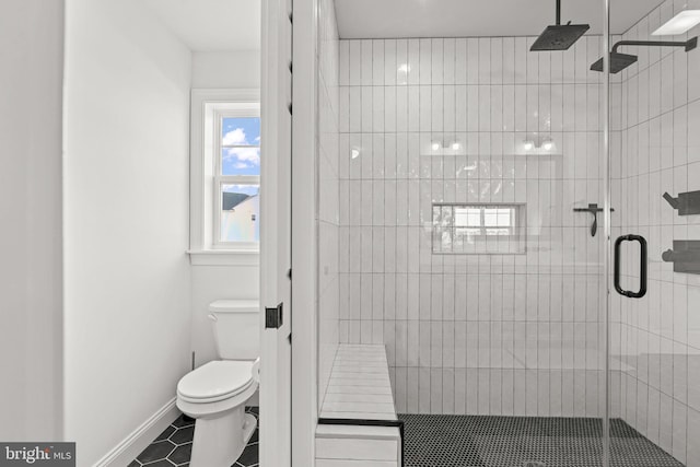 bathroom featuring toilet, a shower with shower door, and tile patterned flooring