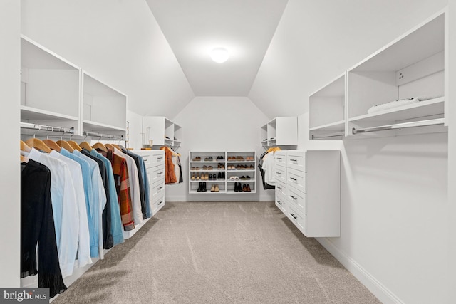 walk in closet with lofted ceiling and light colored carpet