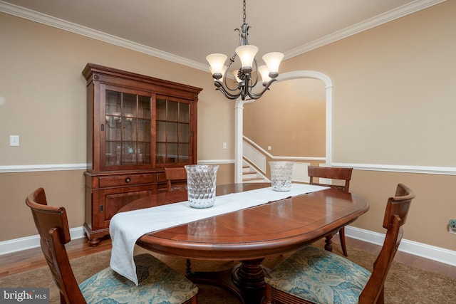 dining area with ornamental molding, hardwood / wood-style flooring, and an inviting chandelier