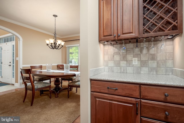 kitchen with backsplash, light carpet, decorative light fixtures, ornamental molding, and an inviting chandelier