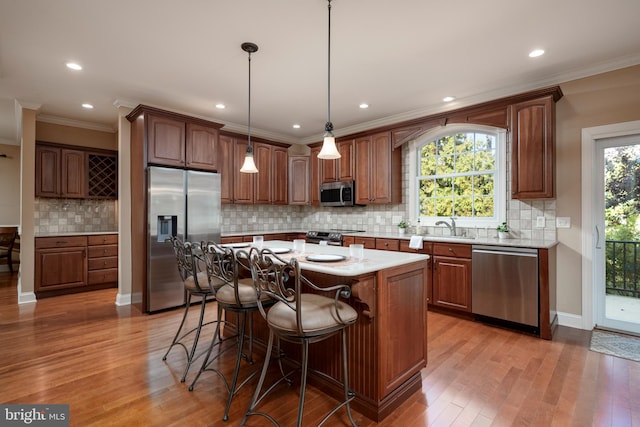 kitchen featuring stainless steel appliances, a center island, light wood-type flooring, and decorative light fixtures