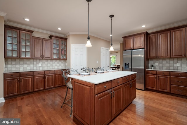 kitchen with light hardwood / wood-style floors, stainless steel fridge with ice dispenser, a center island, and hanging light fixtures