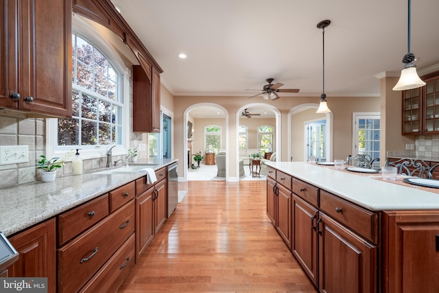 kitchen with a wealth of natural light, hanging light fixtures, light wood-type flooring, and backsplash