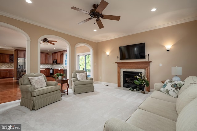 living room featuring ornamental molding, light colored carpet, and ceiling fan