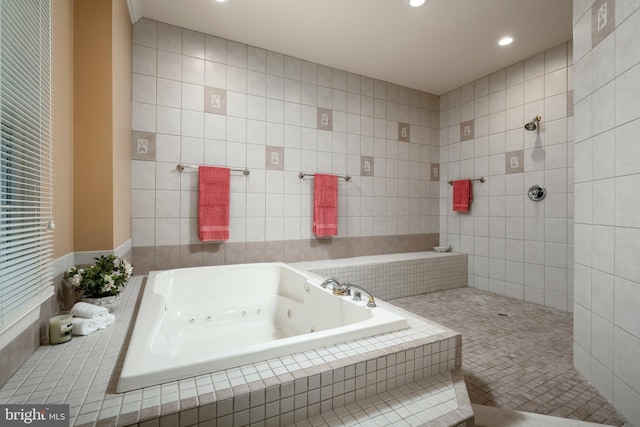 bathroom featuring shower with separate bathtub and tile walls