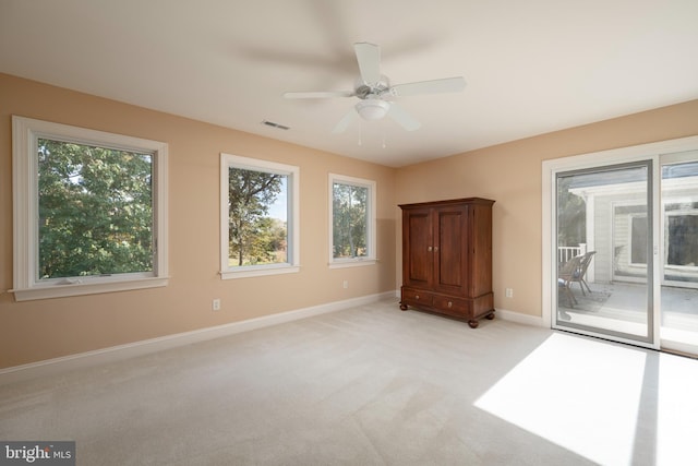 spare room with light carpet, a healthy amount of sunlight, and ceiling fan