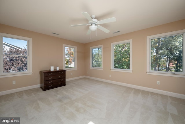 interior space with light carpet, multiple windows, and ceiling fan