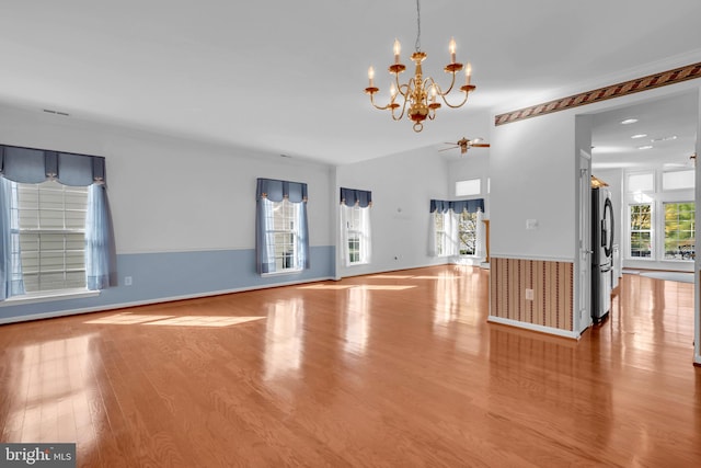 unfurnished living room featuring light hardwood / wood-style floors, a healthy amount of sunlight, and ceiling fan with notable chandelier