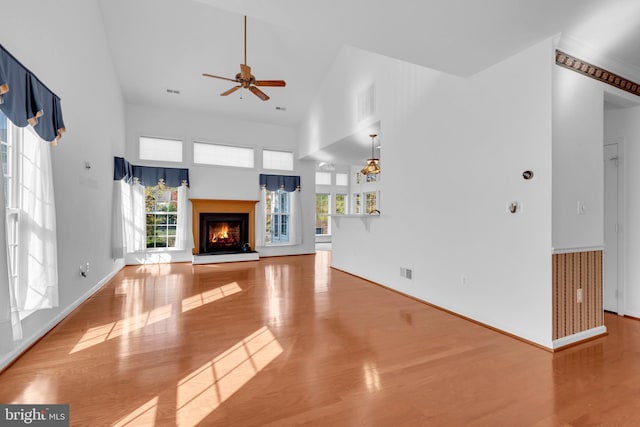 unfurnished living room featuring high vaulted ceiling, a healthy amount of sunlight, light wood-type flooring, and ceiling fan