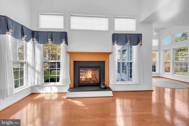 unfurnished living room featuring hardwood / wood-style floors, a towering ceiling, and ceiling fan