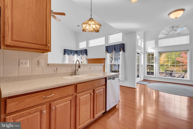 kitchen featuring dishwasher, hanging light fixtures, sink, light hardwood / wood-style floors, and tasteful backsplash