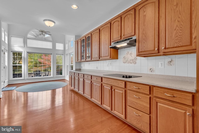 kitchen with decorative backsplash, ceiling fan, light hardwood / wood-style floors, and black electric cooktop