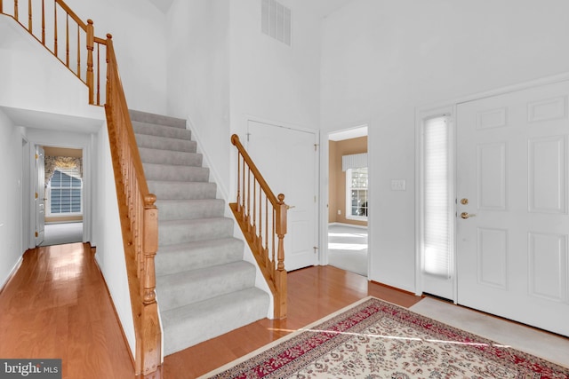 foyer with a high ceiling, plenty of natural light, and hardwood / wood-style floors